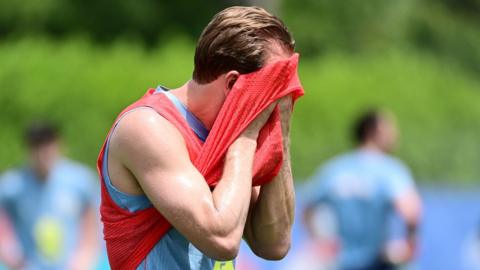 Harry Kane wiping sweat from his face with a training bib