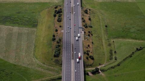An aerial view of the M5 motorway near Tewkesbury in Gloucestershire, with green fields either side.