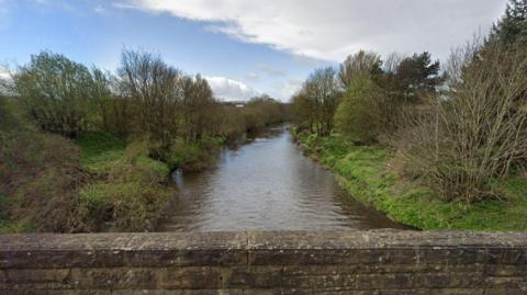 River Almond from a bridge. There are trees and bushes on the bank of the river.