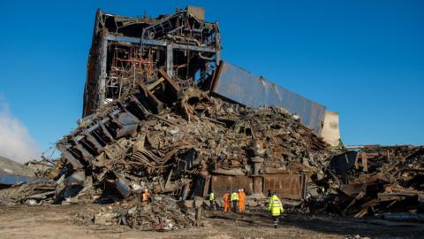 Didcot Power Station building collapse. A few workers are seen below the mountain of rubble.