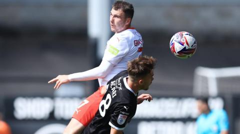 Ryan Graydon of Fleetwood Town and Lewis Macari of Notts County go up for a header