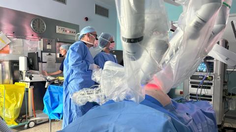 A patient lying on an operating table with robotic arms over his stomach
