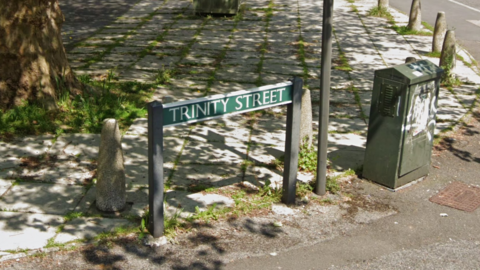 A green street sign which says 'Trinity Street' in white writing.