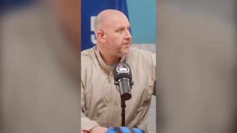 Steve Bracknall sits behind a microphone