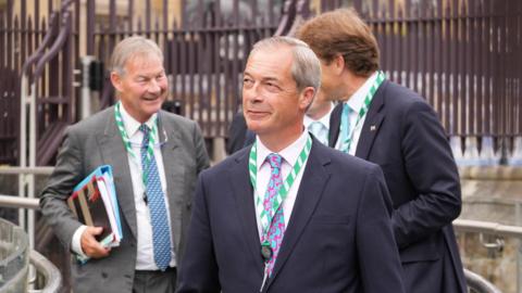 Nigel Farage and Rupert Lowe outside the Houses of Parliament, with the figure of Richard Tice just behind Farage. All are dressed in smart suits and ties, with Lowe carrying two folders. The picture was taken in July 2024, just after the general election.