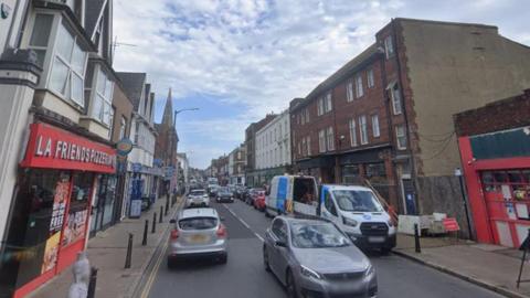 Cars and shops on a busy street.
