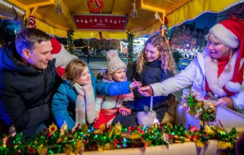 People wrapped up in winter clothing in a marquee that is decorated for the festive season