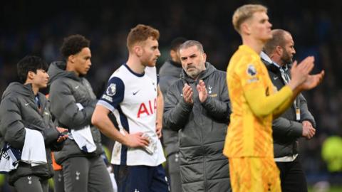 Ange Postecoglou claps his hands next to Tottenham players