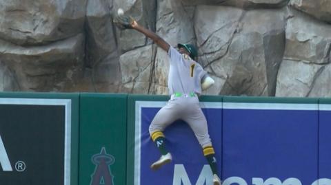 Baseball player Denzel Clarke jumping over wall to catch ball 
