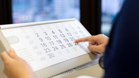 A picture of someone pointing at a calendar.