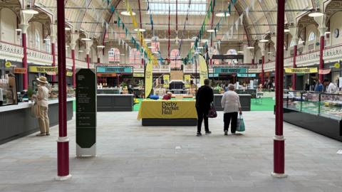 Inside Derby's new Market Hall, showing some empty pop up stalls and few customers