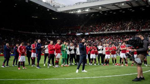 Ruben Amorim stands on the pitch in front of his Manchester United players speaking to the Old Trafford crowd through a microphone