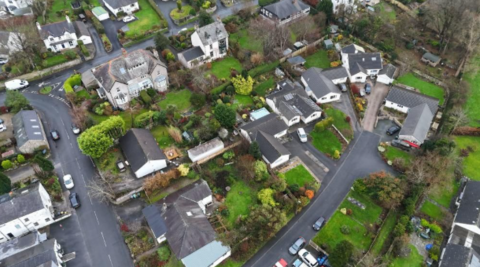 An aerial view of a residential area full of large houses surrounded by trees and greenery