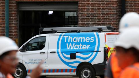 A Thames Water van with some workers blurred in the forefront 
