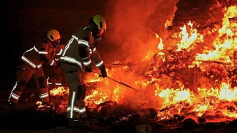 South Yorkshire Fire & Rescue Service firefighters wearing protective gear tackle a blazing wildfire.