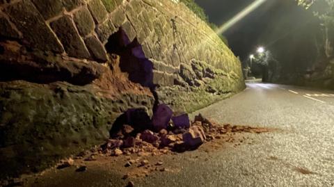 A crumbled wall at night with masonry in the way of traffic