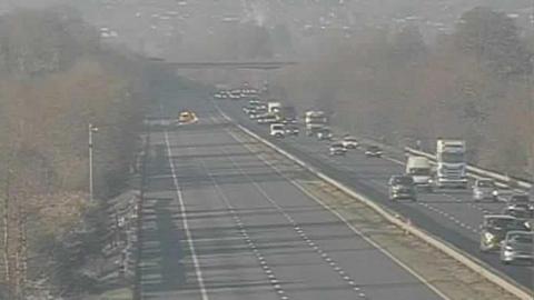 A screenshot from the motorway camera showing the southbound carriageway completely clear of cars, with an emergency vehicle visible in the distance. On the right, cars and lorries are driving down the northbound carriageway. 