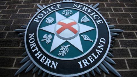 Police Service of Northern Ireland crest hanging on a red brick wall