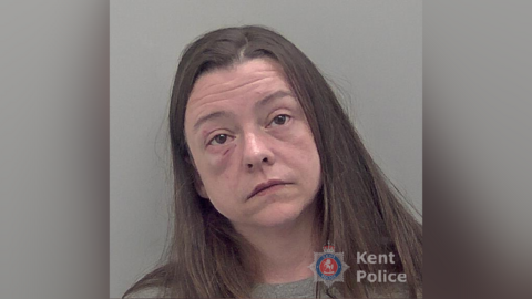 A mugshot of a woman with long brown hair sporting a cut and swollen right eye. 