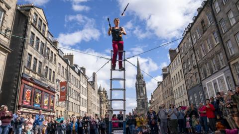 Tourists watch a street performer on the Royal Mile