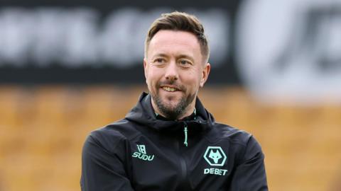 Ian Burchnall wearing a jacket with Wolves logo while looking on at a training session