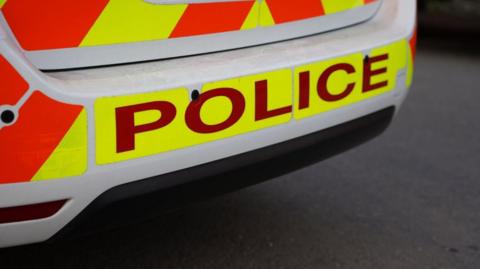 The rear end of a police car focused in on the word 'Police' 