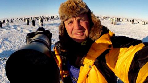 Nature photographer Doug Allan with penguins behind him