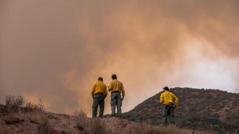 Firefighters speak on the radio as the so-called 'Line Fire,' a wildfire burning in the foothills of the San Bernardino National Forest, in Mentone, California