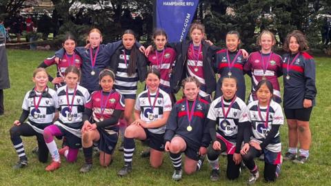 A team photo of the Vectis RFC girls team, with one row on their knees and another stood behind them.