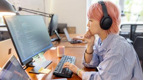 Woman looking at screens showing computer-programming applications