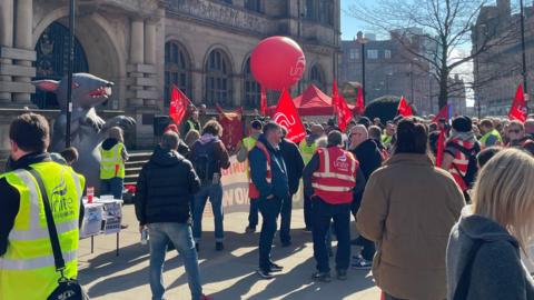 The demo outside Sheffield Town Hall, with people waving red Unite banners, balloons and flags.