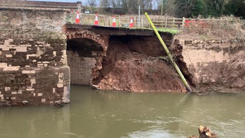 The remains of a 15th-century bridge structure, with part of the brickwork exposed. 