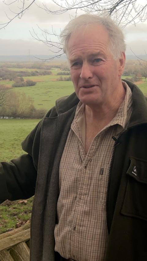 Elderly balding man with white hair wearing jacket in a field