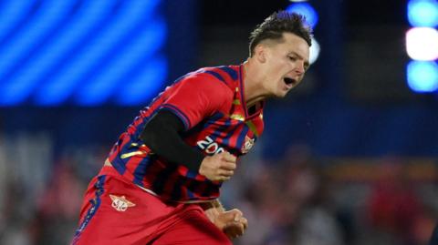 Sonny Baker of Manchester Super Giants, in the team's red and blue kit, celebrates a wicket