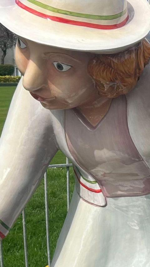 Sculpture of a woman bowler wearing her white bowling jumper, skirt and hat