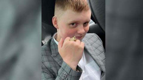 Conner Loder wearing a grey suit jacket and gold ring on his middle finger