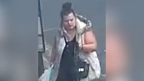 A blurry CCTV image of a woman carrying a bag