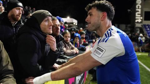 Macclesfield's Sam Heathcote is consoled by fans after his own goal settled the FA Cup fourth round tie against Brentford.