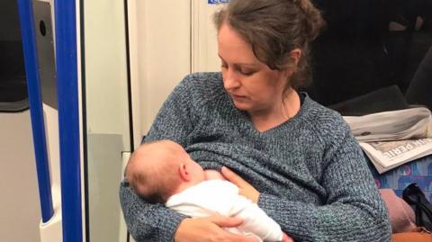 A woman breastfeeding her baby on the tube.