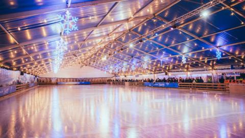 A large ice rink in Weston with bright lights and snowflakes hanging down from the ceiling.