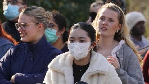 Students queue up for vaccine outside - many are wearing face masks