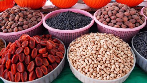 A selection of dried fruits and nuts in open baskets at a market