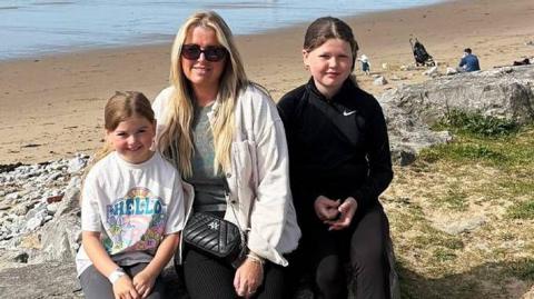 Lucy a'i dwy ferch ar y traeth