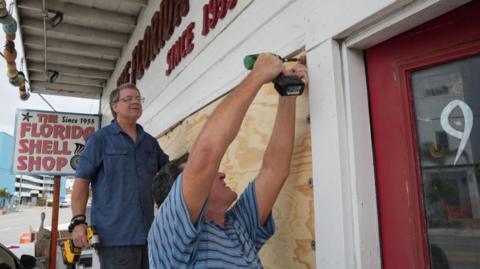 two men boarding up a shop front in Florida.