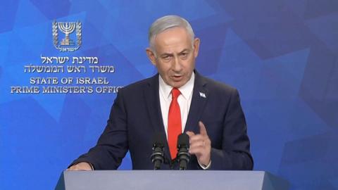 Netanyahu in front of a blue wall wearing a suit