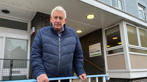 Councillor Mike Mitchelson standing outside the entrance to Moor Lodge in Brampton