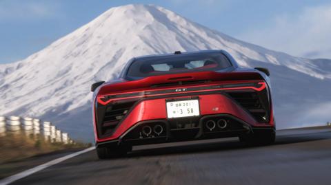 Screenshot shows the back of a red sports car as it races along a mountain road towards the snow-capped peak of Mt Fuji.