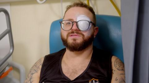 Adam Harcombe in hospital with a bandage on his left eye following surgery