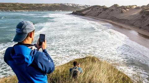 Two researchers take images of the changes to the sand dunes along the shoreline at Crantock after Storm Lorenzo in 2019.