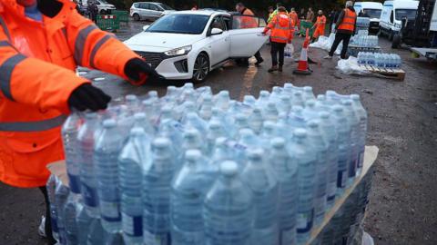 Volunteers from South-East Water assist members of the public load bottled water into their vehicles at a distribution point
